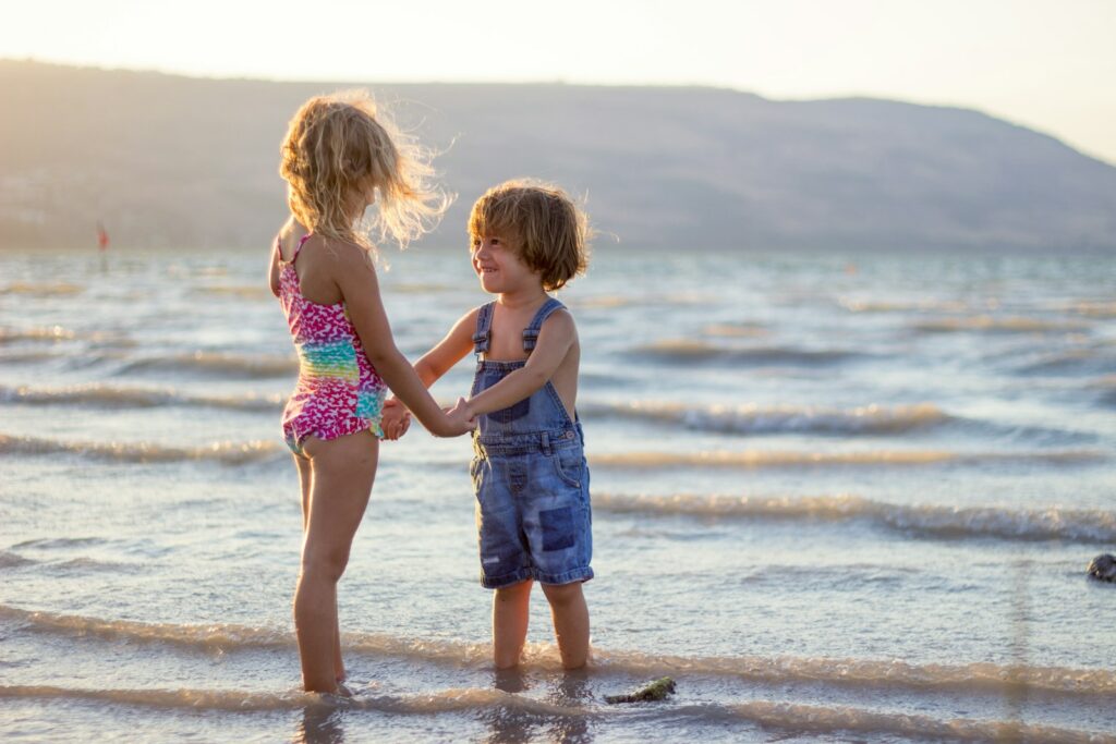 two girls standing on seashore