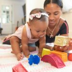 a woman and a baby playing with toys on a blanket